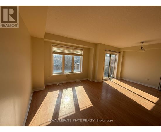 A sunny room with wooden floors and a large window.