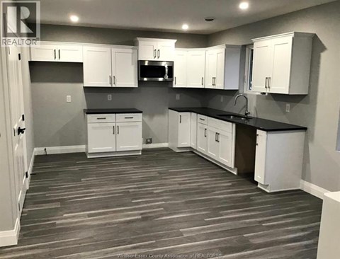 A kitchen with white cabinets and a black countertop.