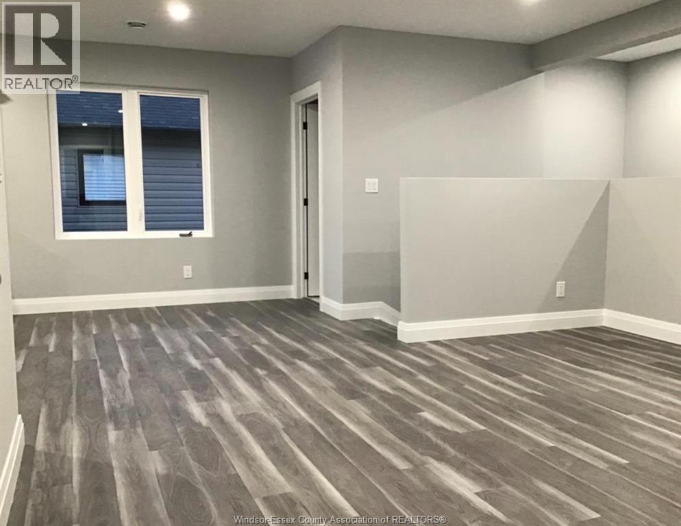 A room with grey wooden flooring and a window with blinds.