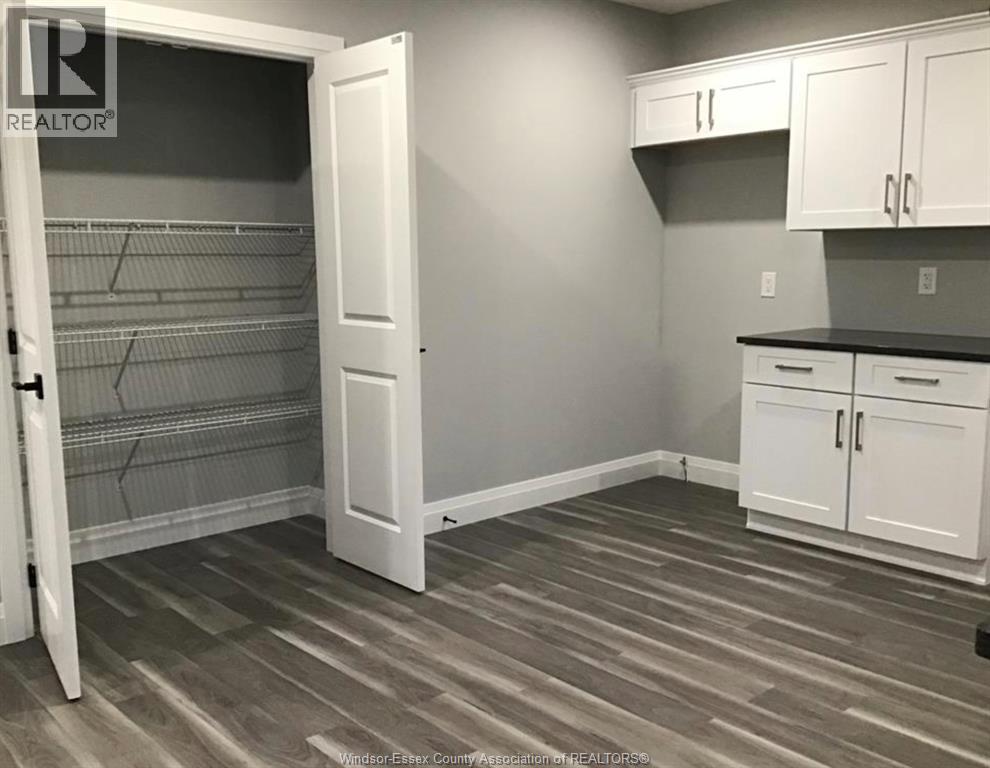 A room with a grey floor and white cupboards.