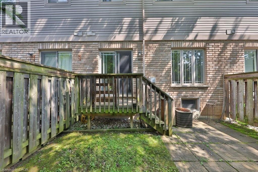 A backyard with a wooden deck and a brick building in the background.