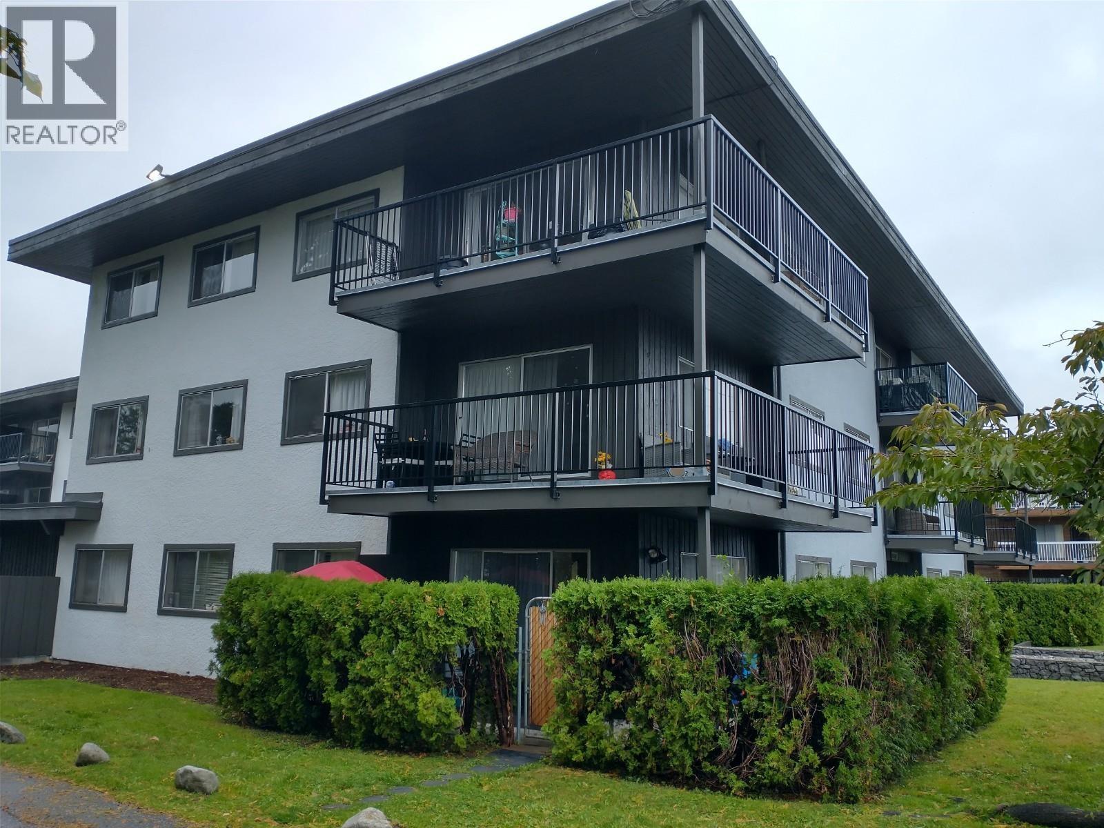 A large white and black building with a balcony and a small red umbrella.