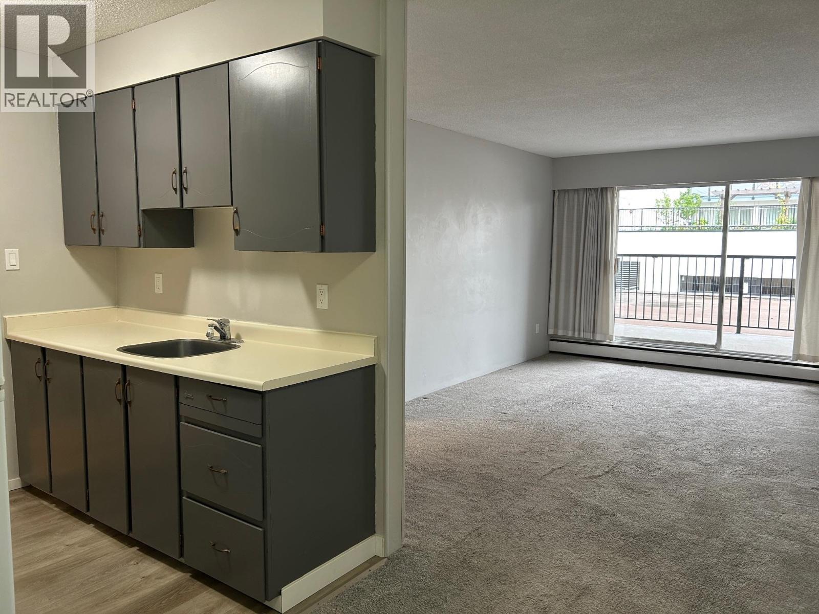 A kitchen with a sink, cabinets, and a window.