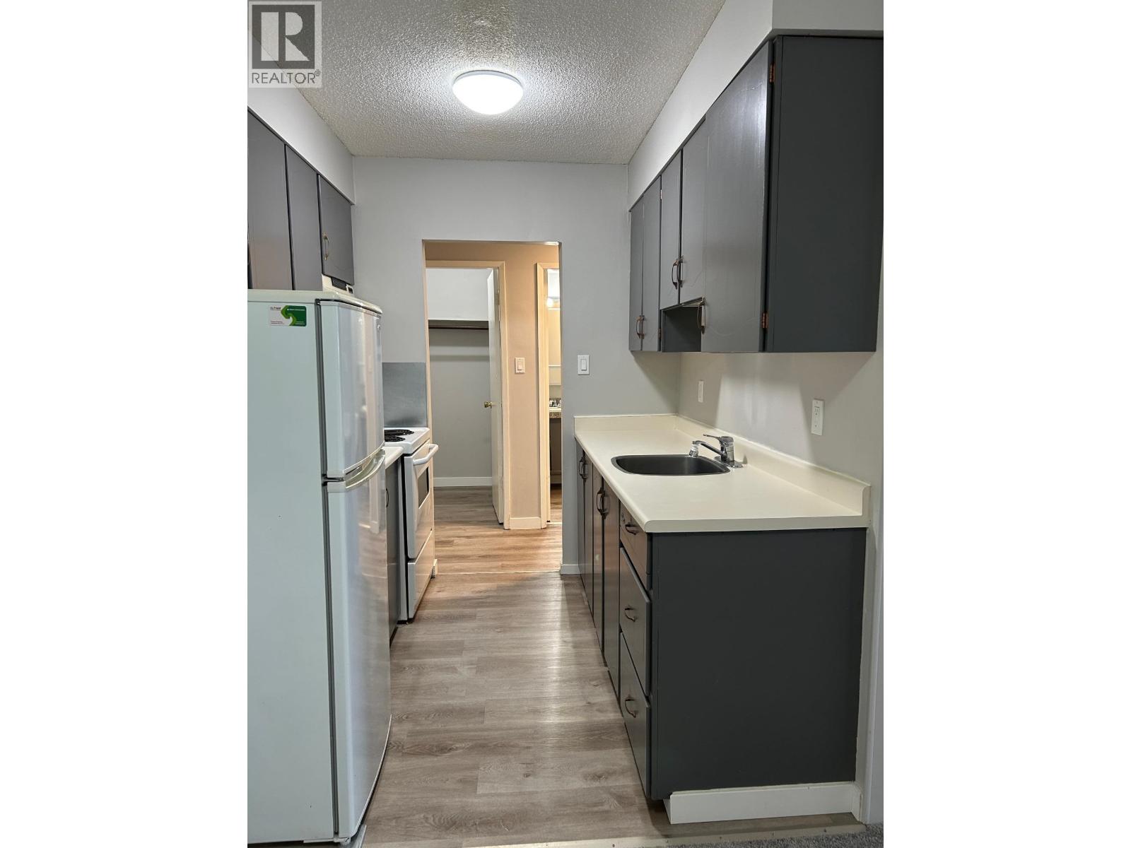 A kitchen with a white fridge and black cabinets.