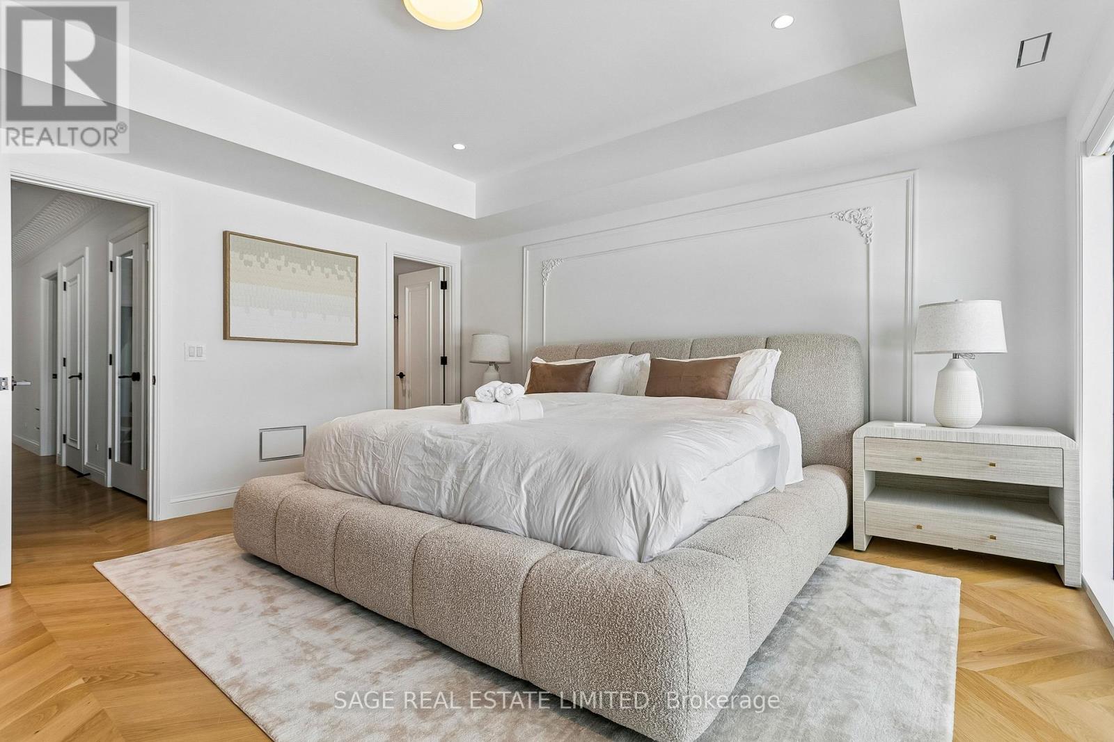 A bedroom with a large bed and a wooden floor.