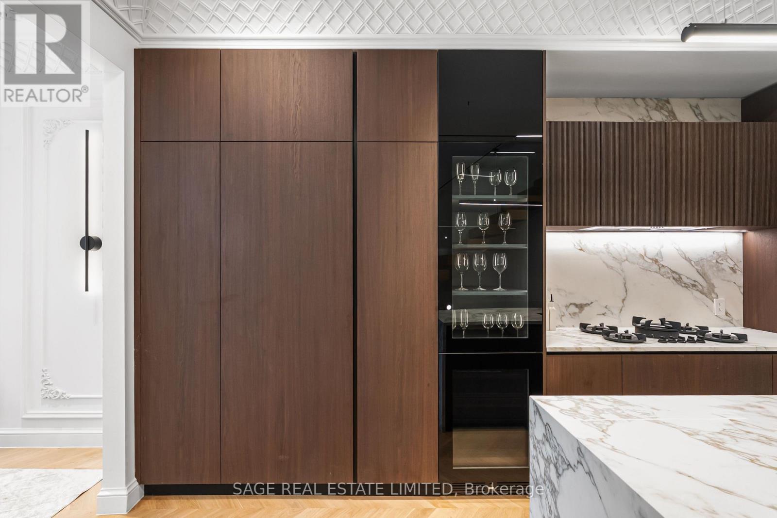 A modern kitchen with dark wood cabinets and a marble countertop.
