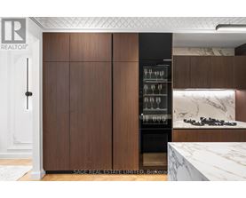A modern kitchen with dark wood cabinets and a marble countertop.