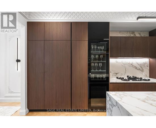 A modern kitchen with dark wood cabinets and a marble countertop.