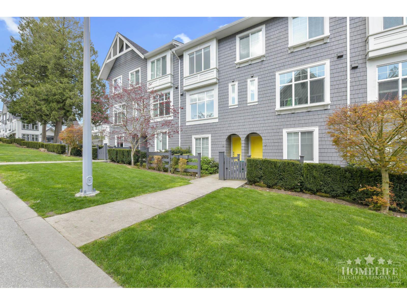 A grey apartment building with a green lawn in front.