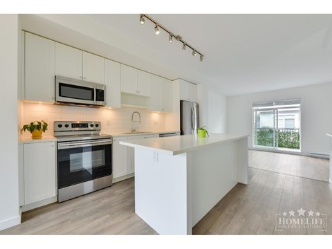 A modern kitchen with white cabinets and stainless steel appliances.