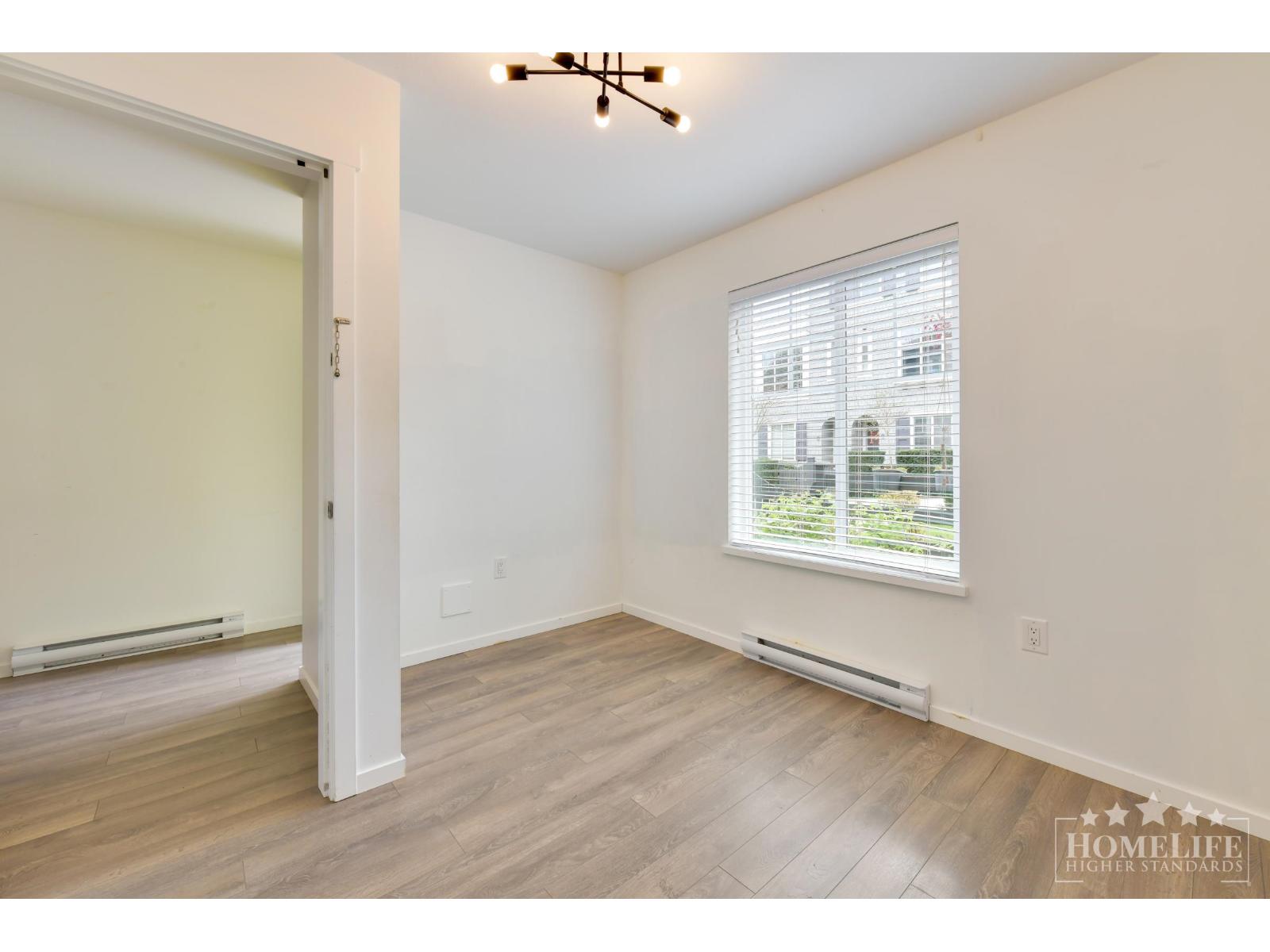 A room with a window and a wooden floor.