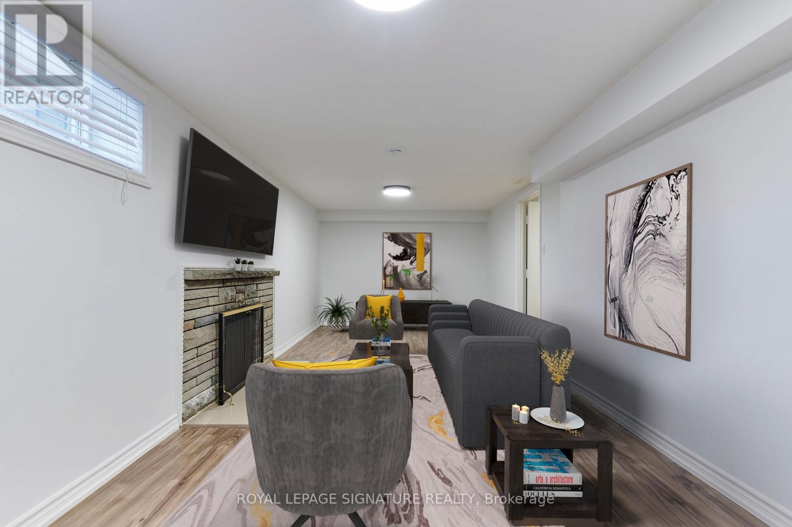 A living room with a grey couch, a coffee table, and a television mounted on the wall.