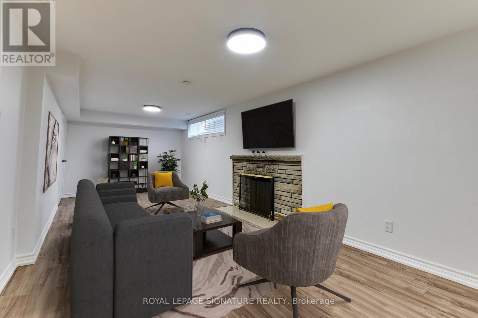 A living room with a grey couch, a fireplace, and a television.