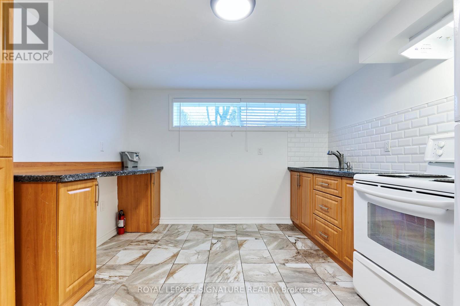 A kitchen with a white stove top oven and wooden cabinets.