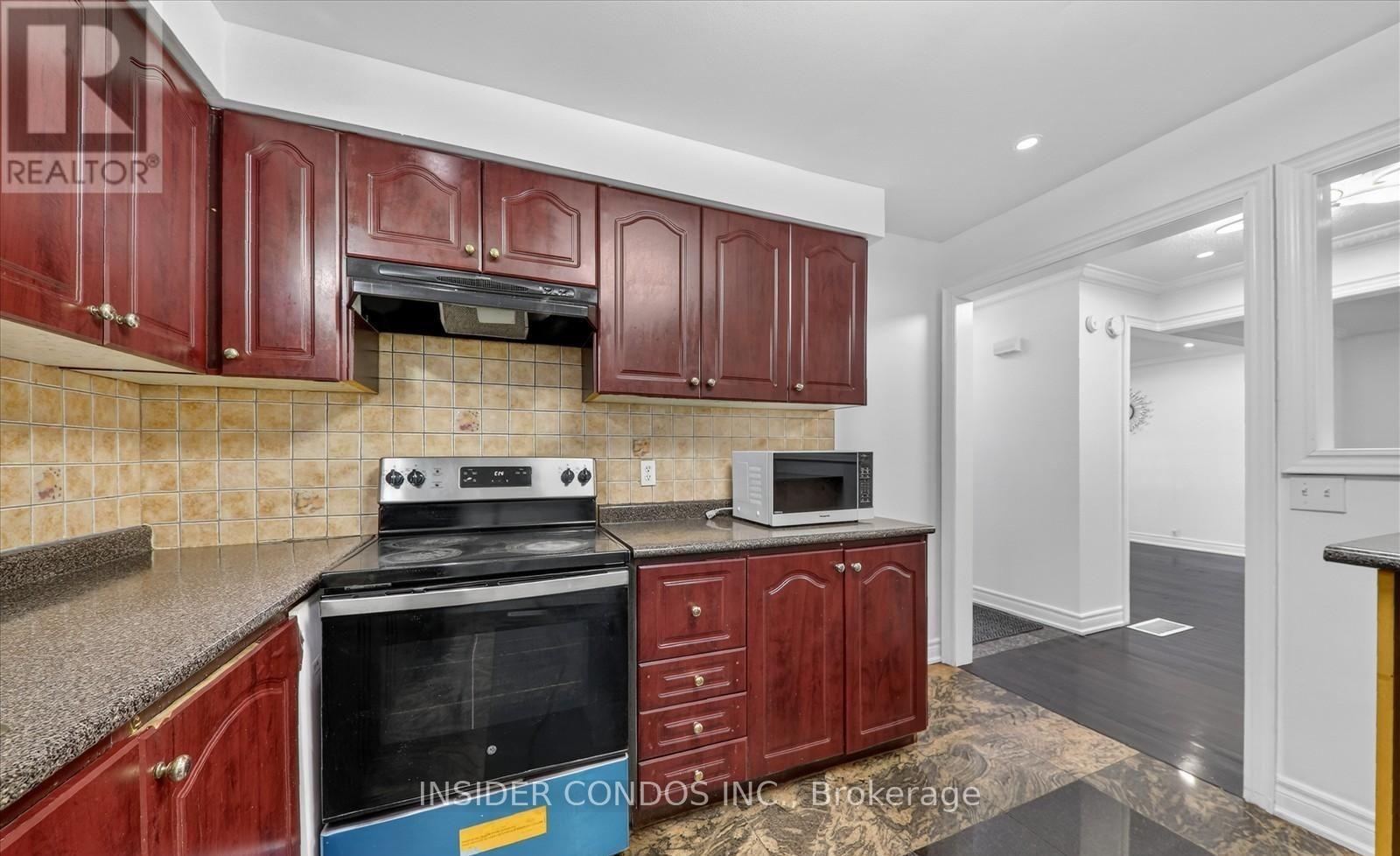 A kitchen with red cabinets and a stove top oven.