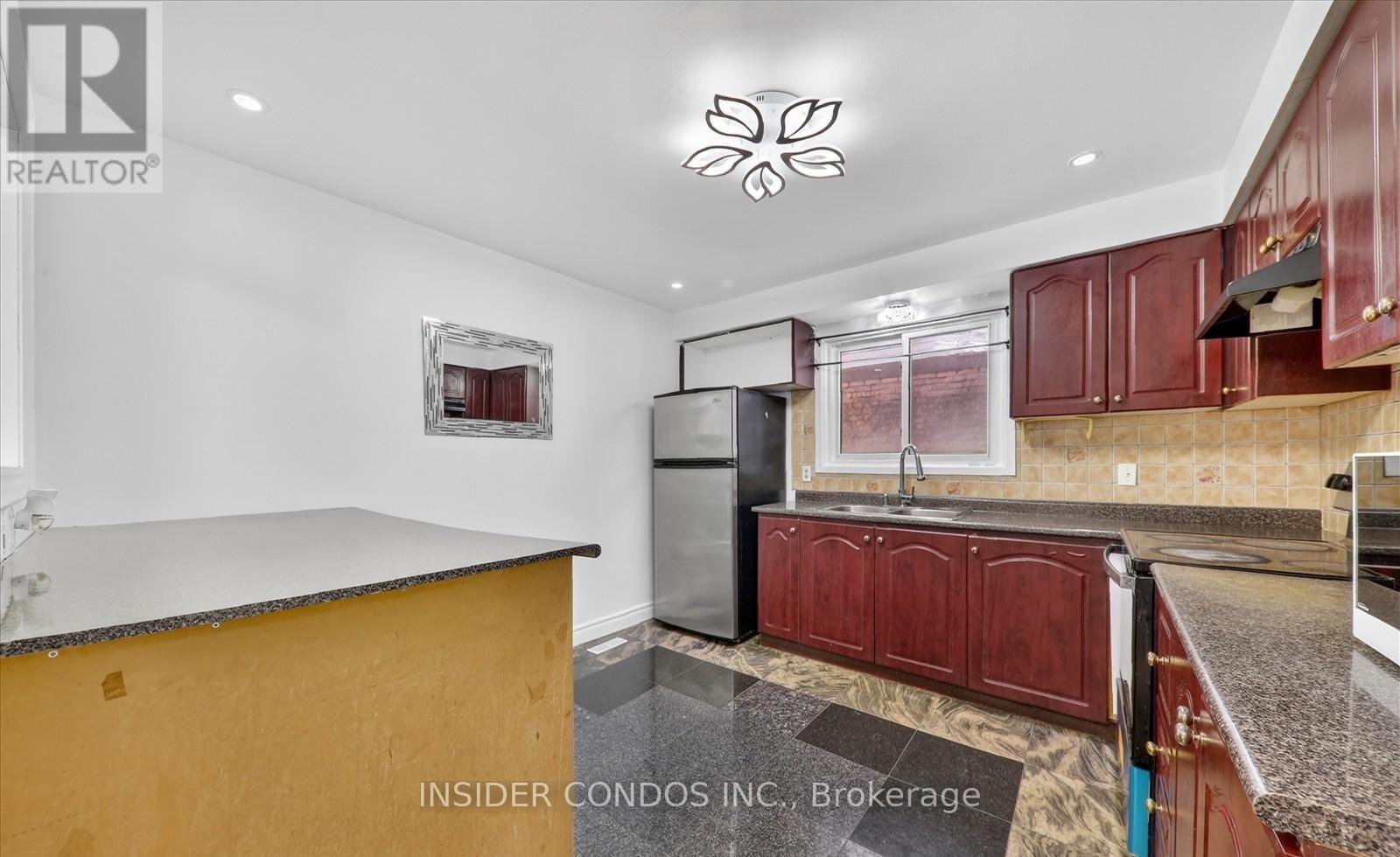 A kitchen with a refrigerator, sink, and cabinets.
