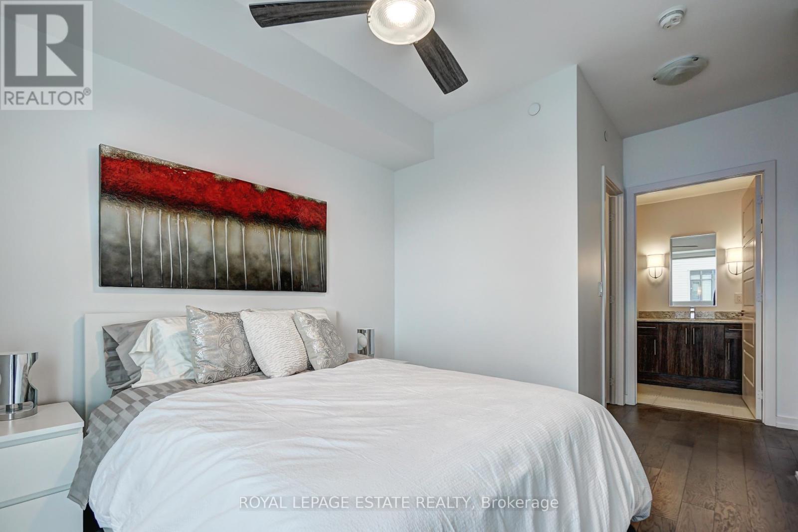 A bedroom with a bed, pillows, and a ceiling fan.