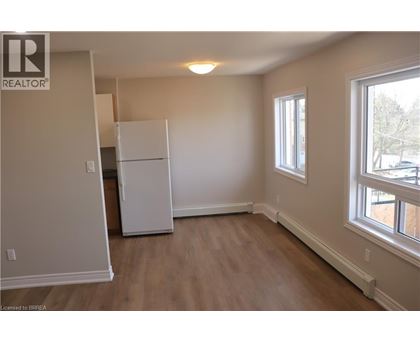 A white refrigerator in a room with wooden floors and a window.
