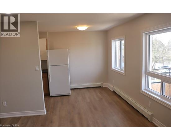 A white refrigerator in a room with wooden floors and a window.