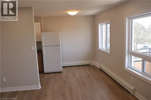 A white refrigerator in a room with wooden floors and a window.