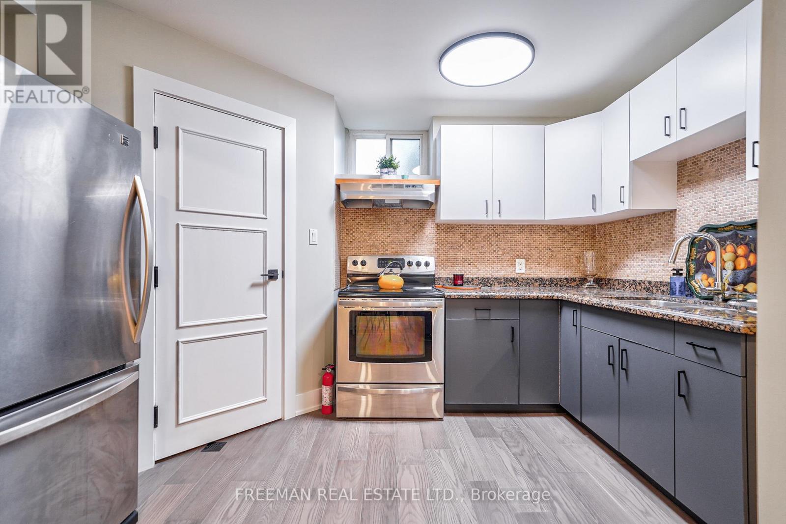 A kitchen with a stainless steel refrigerator and a wood stove.
