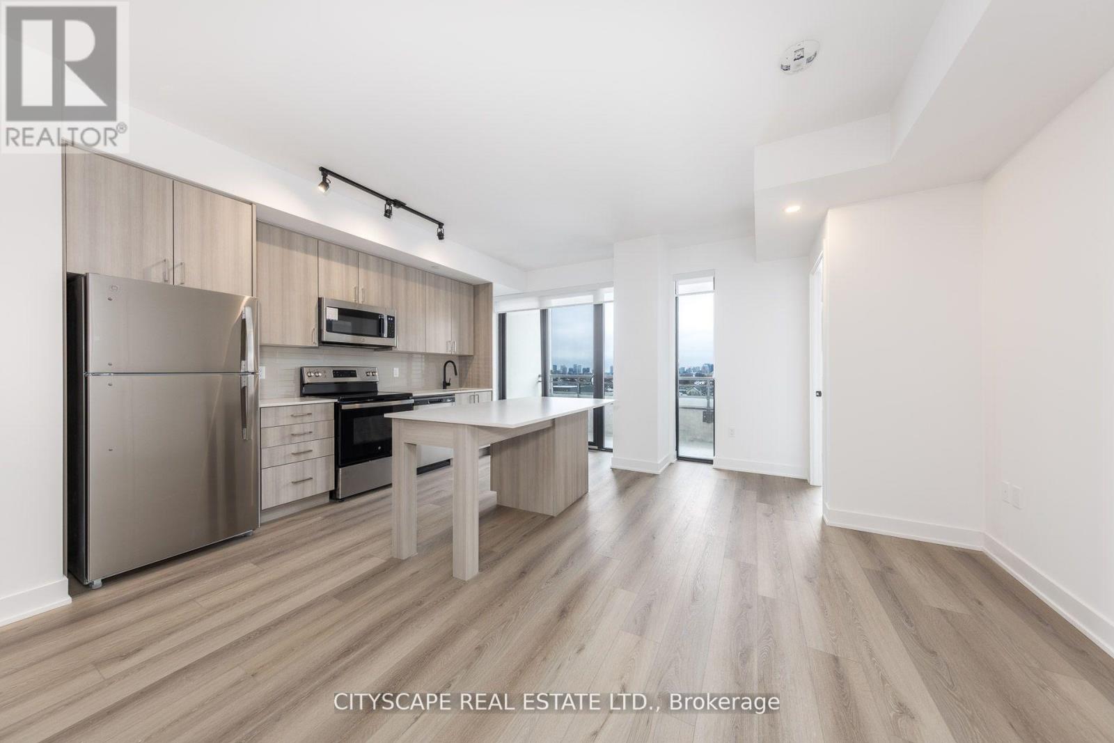 A kitchen with a refrigerator, oven, microwave, and a dining table with chairs.