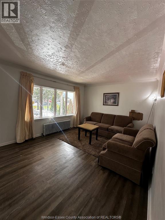 A living room with a brown couch and a window with curtains.