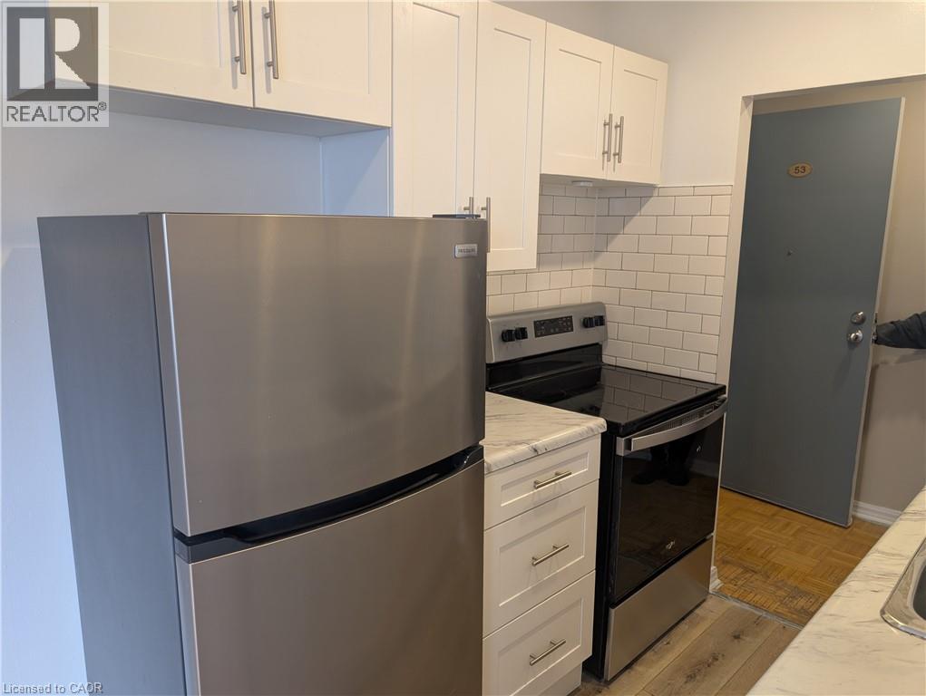 A kitchen with a stainless steel refrigerator and white cabinets.