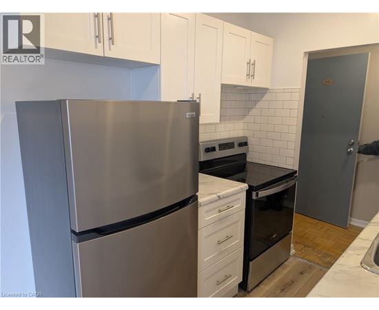 A kitchen with a stainless steel refrigerator and white cabinets.