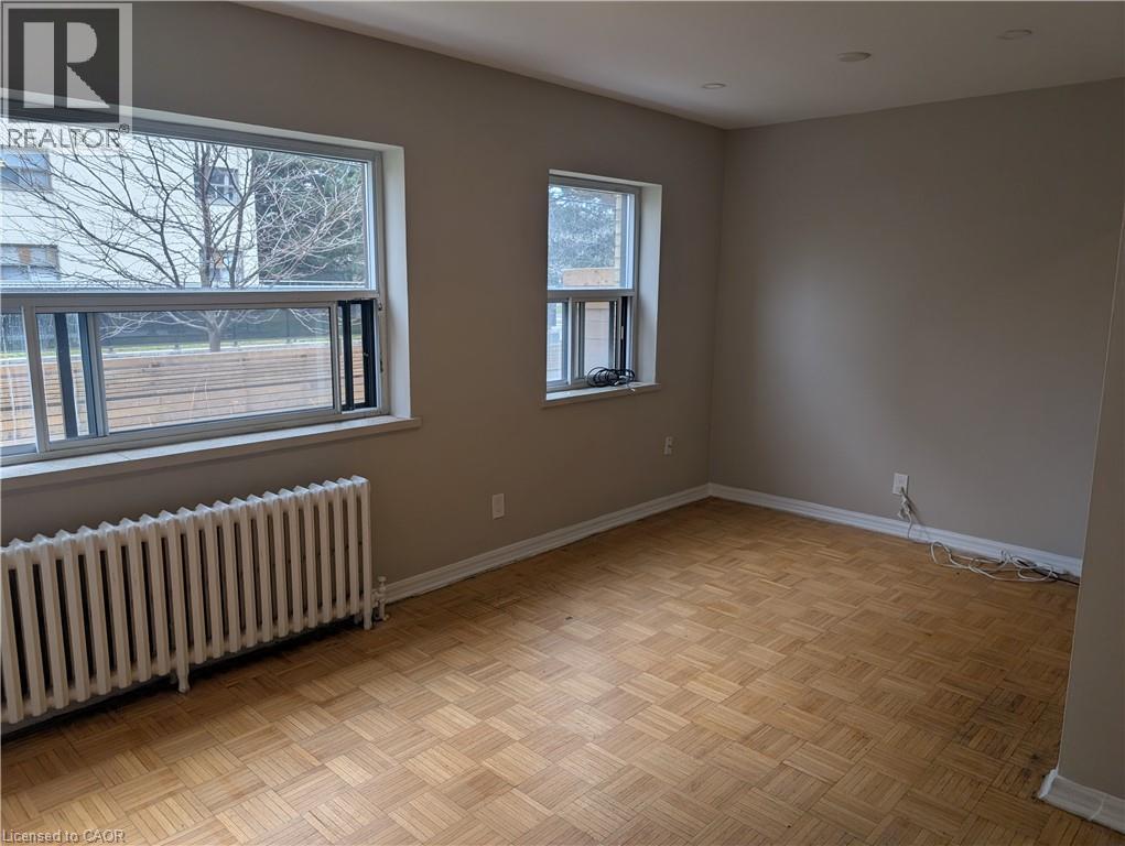 A room with wooden flooring and two windows.