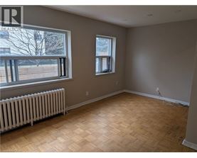 A room with wooden flooring and two windows.