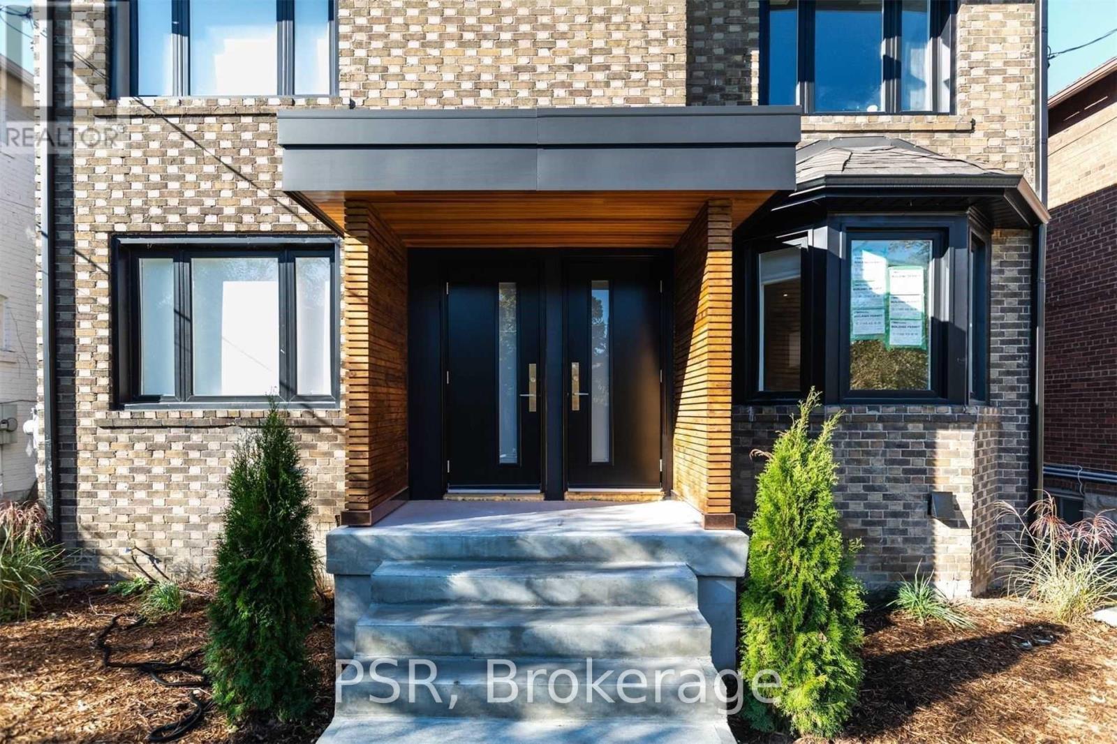 A modern house with a black front door and a brick facade.