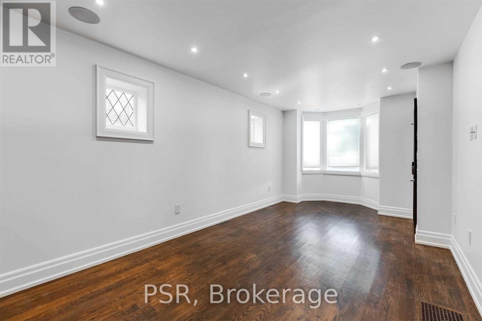 A room with wooden floors and white walls, with a window and a door.