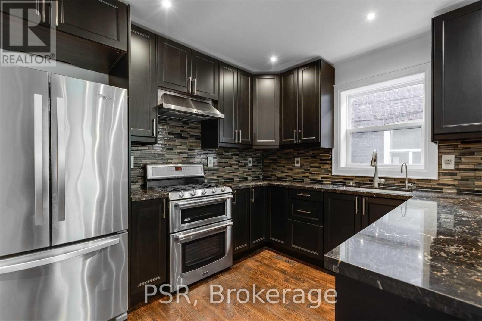 A modern kitchen with dark brown cabinets and a stainless steel refrigerator.