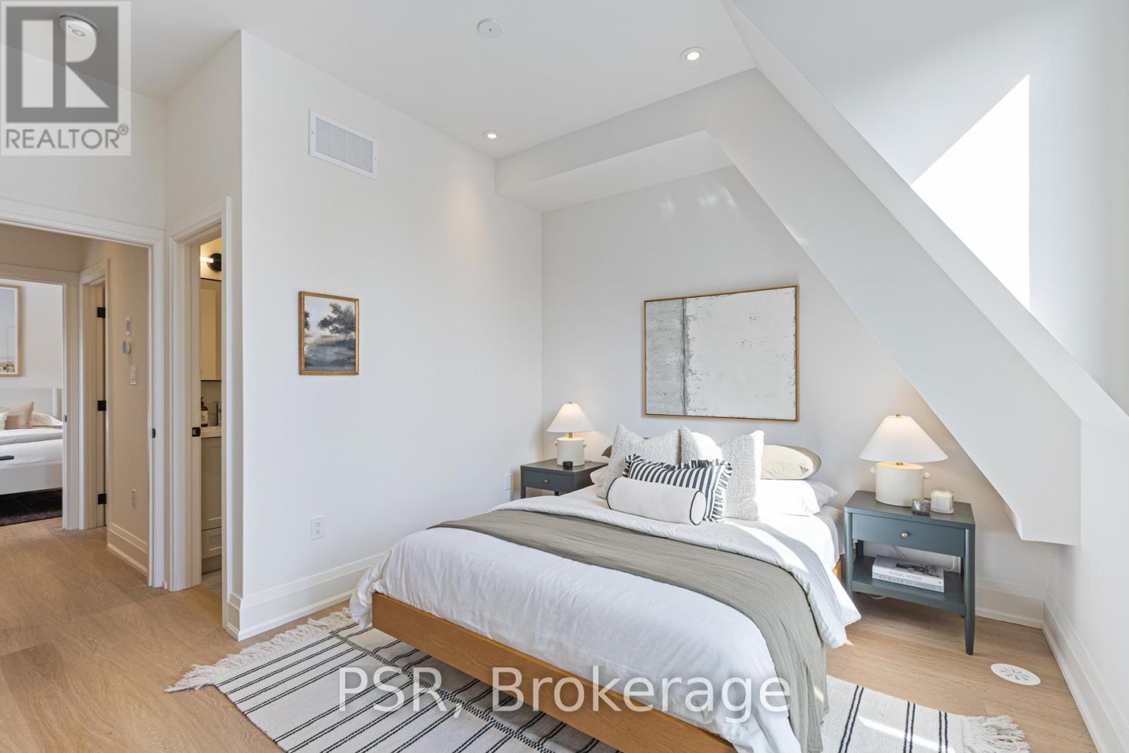 A bedroom with a large bed and a nightstand with a lamp.