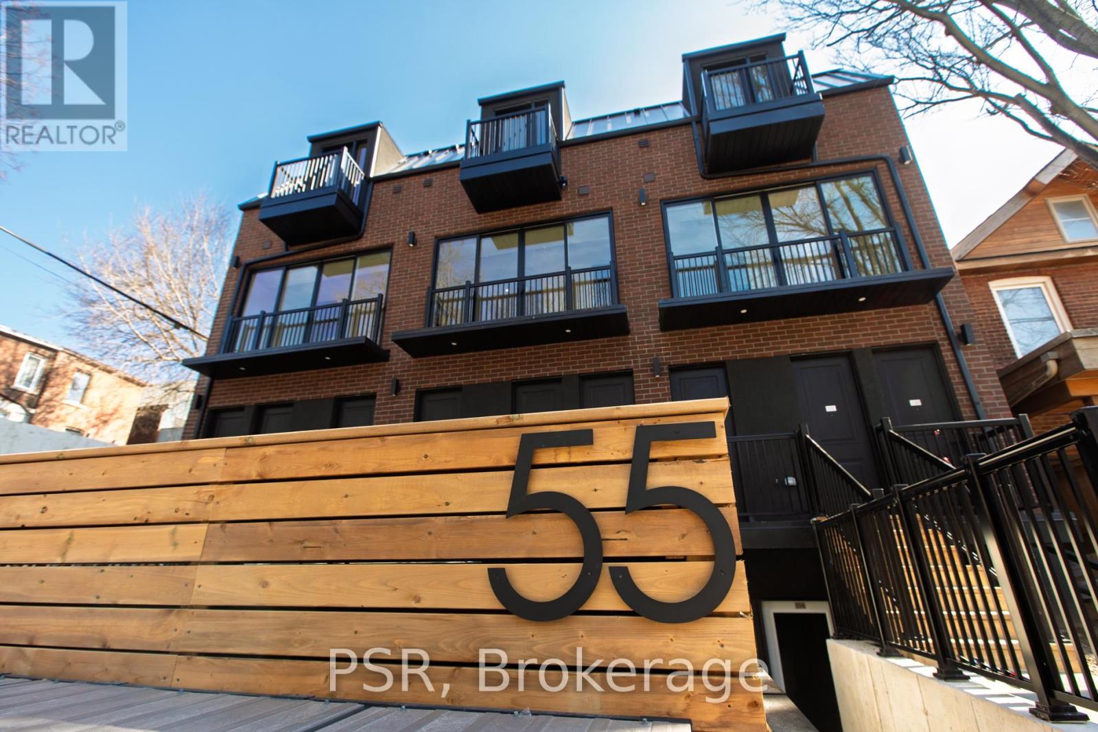 A building with the number 55 on a wooden sign in front of it.