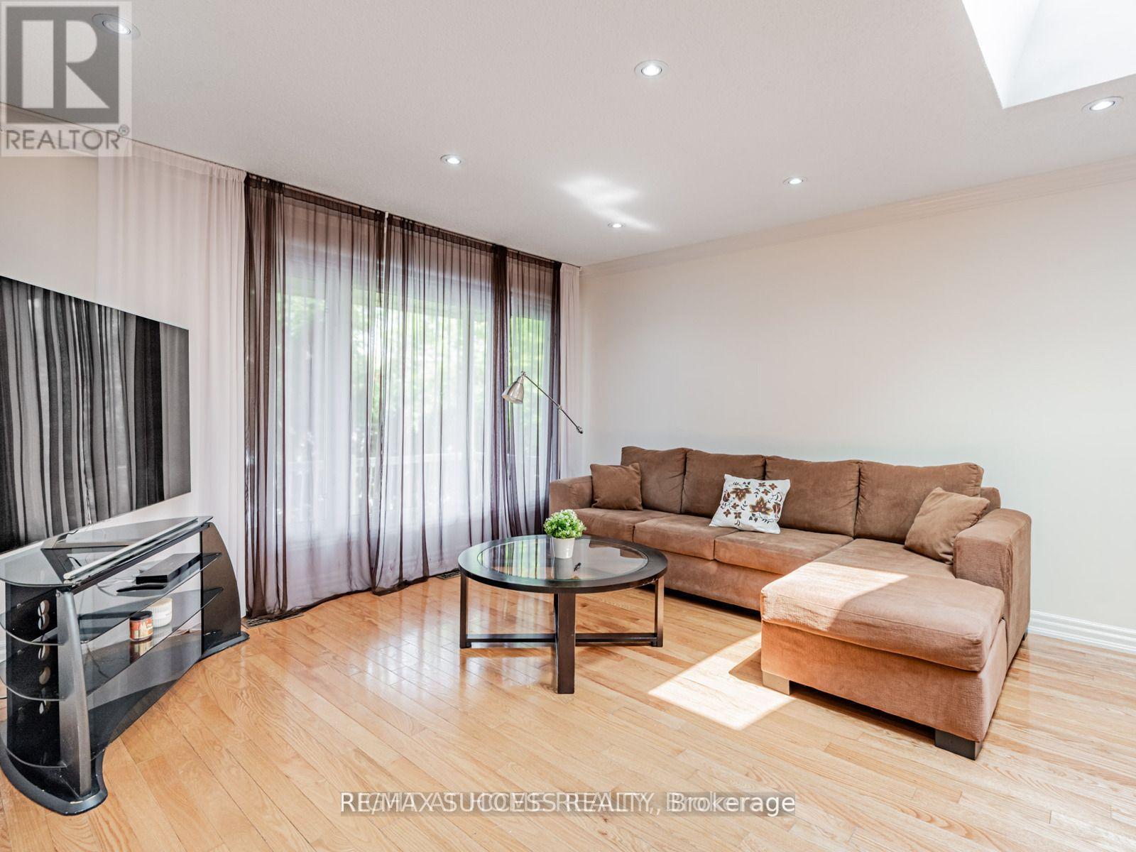 A living room with a brown couch, a glass coffee table, and a television.