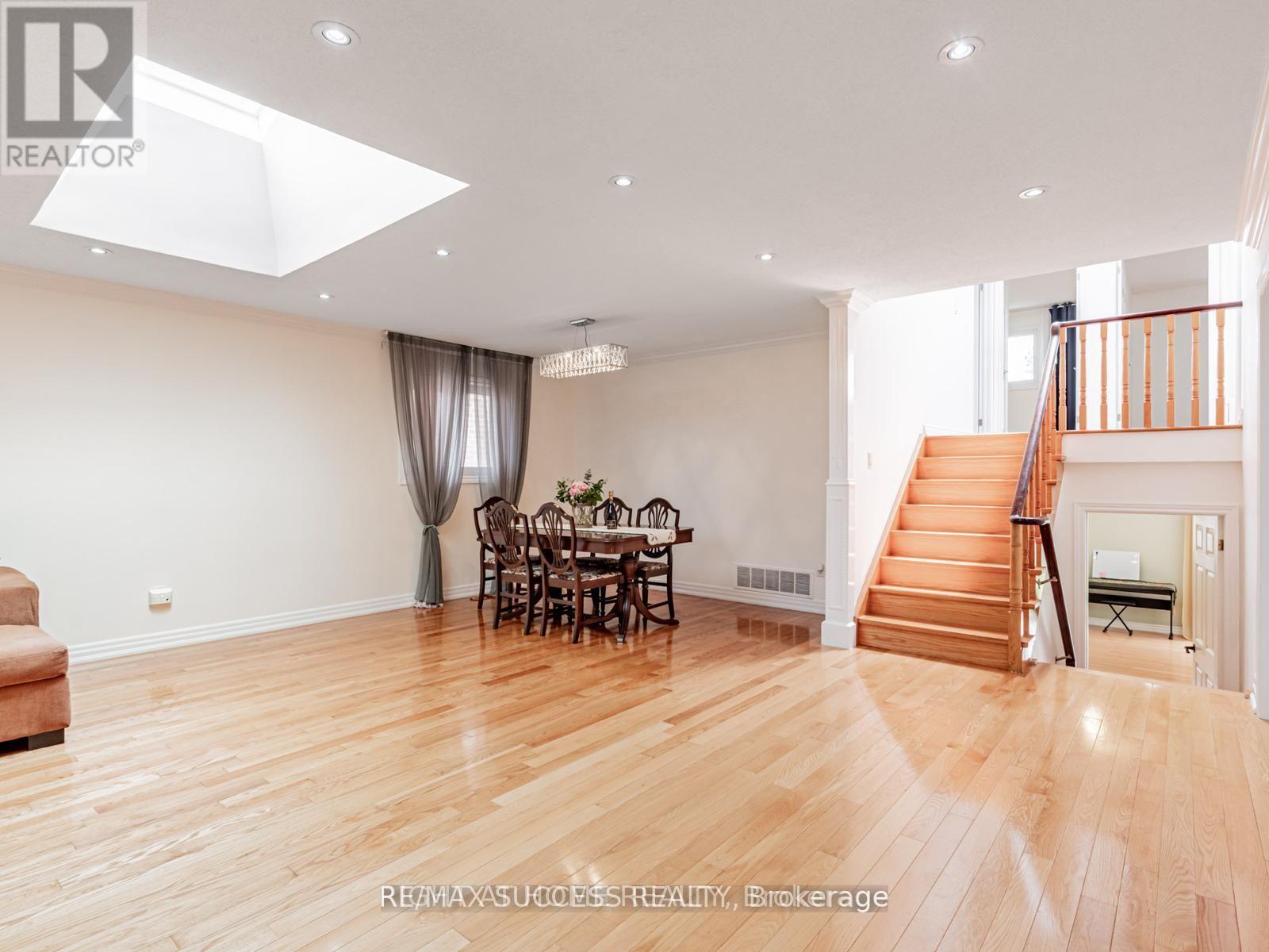 A spacious room with wooden floors and a dining set.