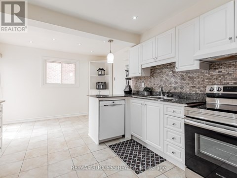 A kitchen with white cabinets and a black and white checkered floor mat.