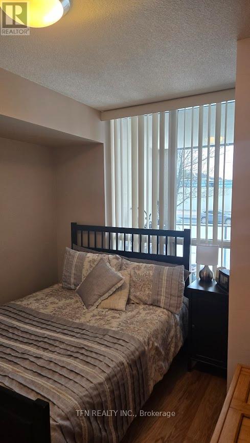 A bedroom with a bed, nightstand, and window with blinds.