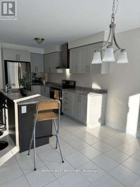 A kitchen with a white tile floor and a hanging light fixture.