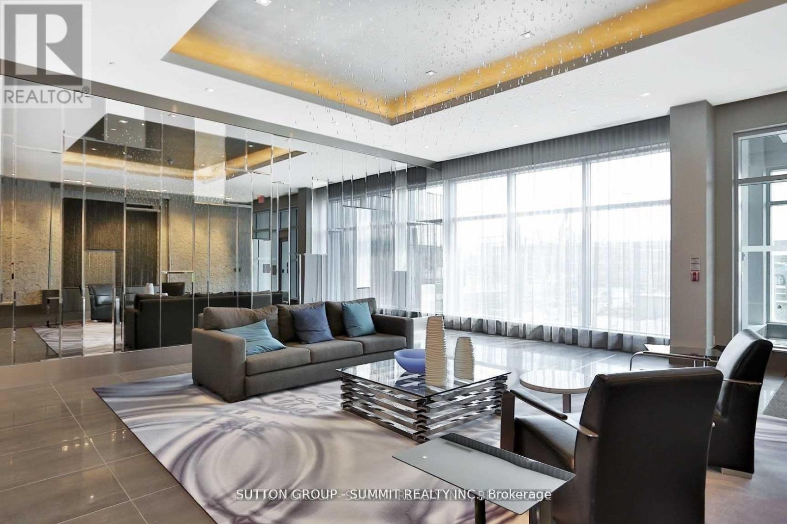A modern living room with a glass wall and a large window.