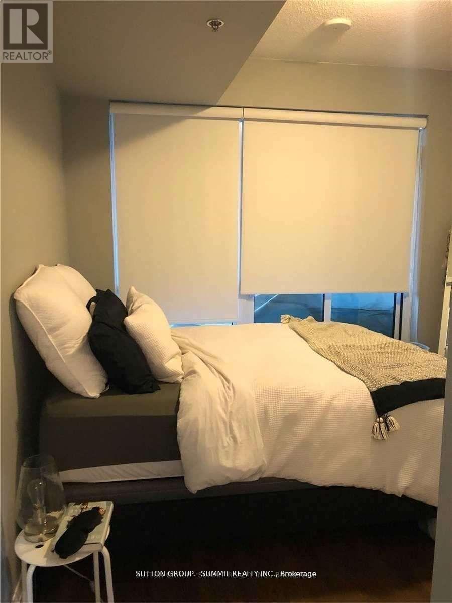 A bedroom with a bed, pillows, and a chair.