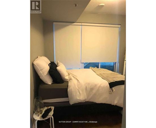 A bedroom with a bed, pillows, and a chair.
