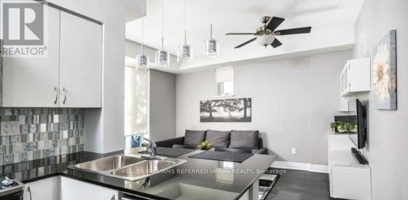 A modern kitchen with a black countertop and a ceiling fan.