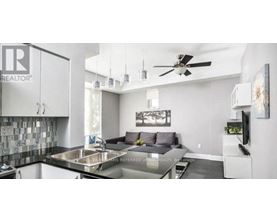A modern kitchen with a black countertop and a ceiling fan.