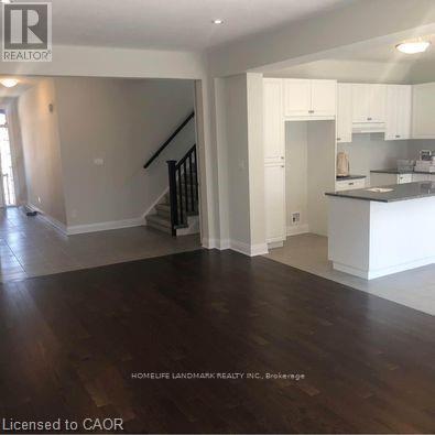 A spacious living room with hardwood floors and a staircase leading to the upper level.
