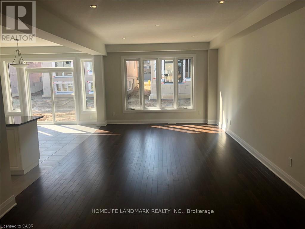 A spacious room with dark hardwood floors and large windows.