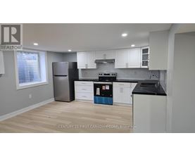 A kitchen with a refrigerator, oven, and cabinets.