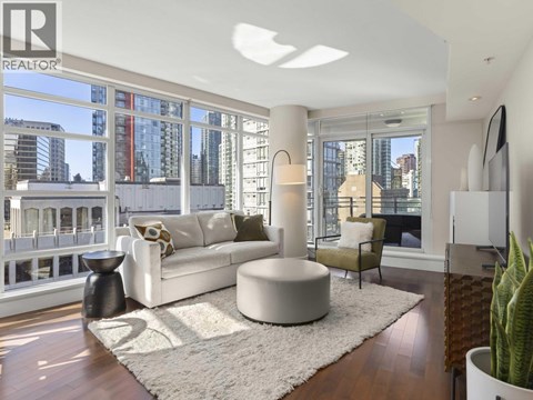 A living room with a white couch and a large window overlooking a city.